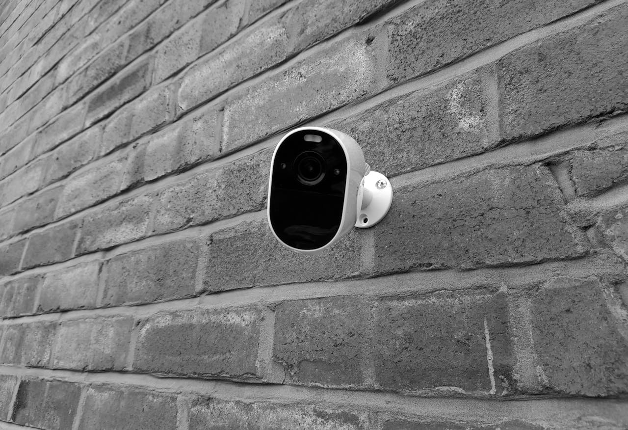 about-us Close-up of a security camera mounted on a brick wall in monochrome.